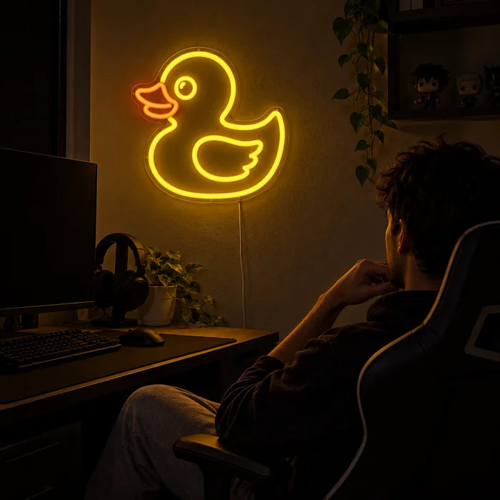 Yellow Duck Neon LED Sign above a gaming desk, a gamer in a gaming chair in front of it