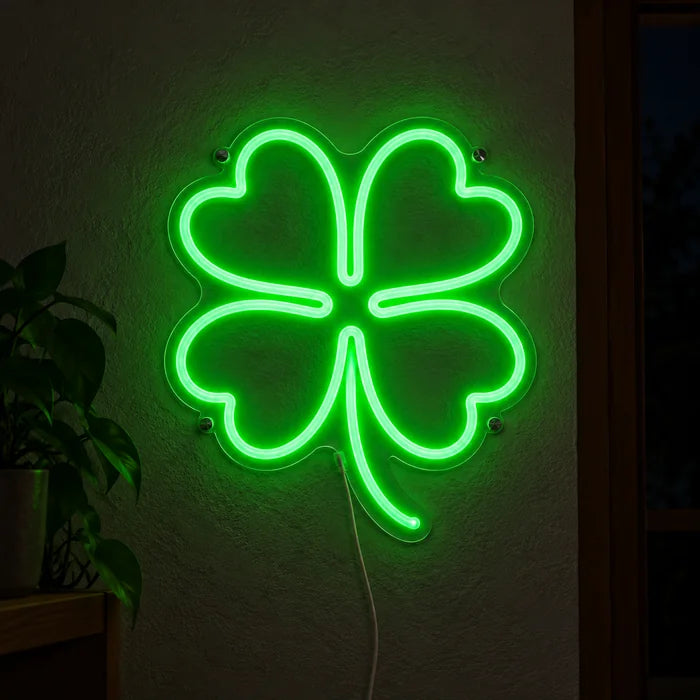 Neon LED-skilt Lykkekløver lysende på en mørk vegg, nærbilde med tilkoblingskabel
