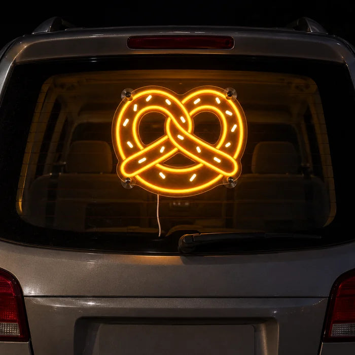 Golden Pretzel Neon LED Sign on the rear window of a car at night