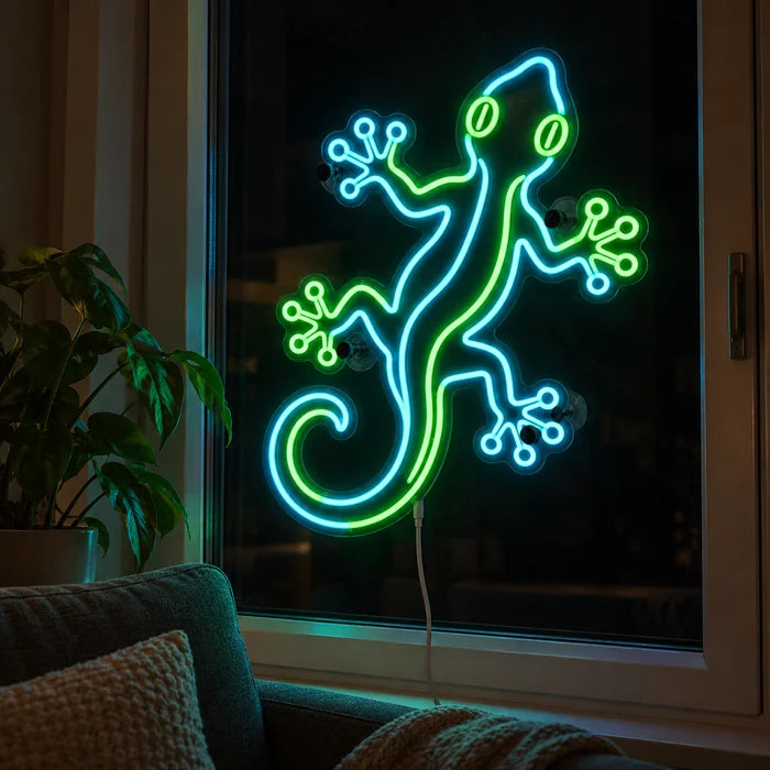 Green Gecko Neon LED Sign in the window of a cosy living room in the evening