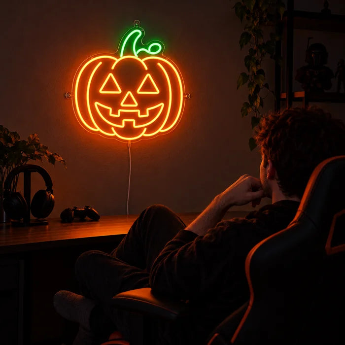 Halloweengræskar neon LED skilt over gaming-skrivebordet, foran en gamer i gamingstolen