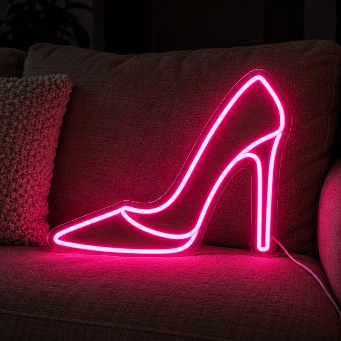 Korkokenkä neon LED -kyltti kodikkaalla sohvalla tyynyjen ja huovan välissä