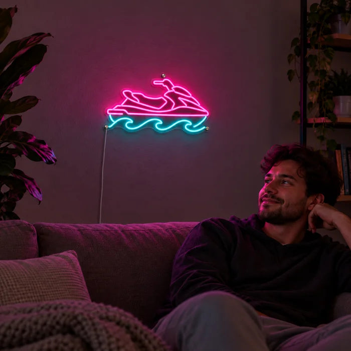 Vesijetti neon LED -kyltti olohuoneen seinällä, edessä henkilö rentoutuu sohvalla