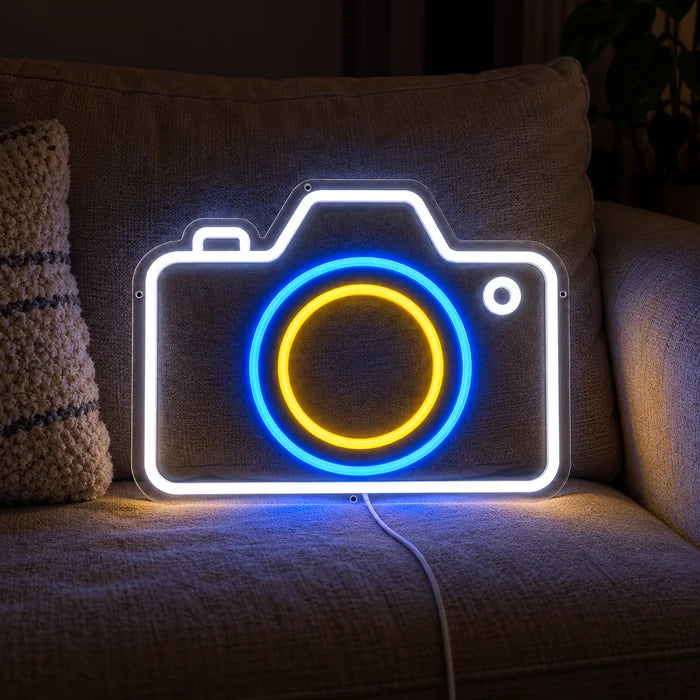 Camera Neon LED Sign on a cosy sofa between cushions and a throw
