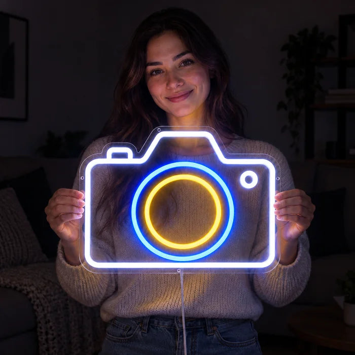 Camera Neon LED Sign held by a smiling woman against a dark background