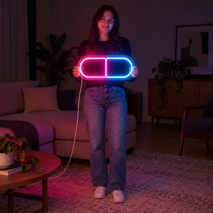 Neonová LED cedule Kapsle léku, drží ji žena, ukazuje velikost ve srovnání s tělem