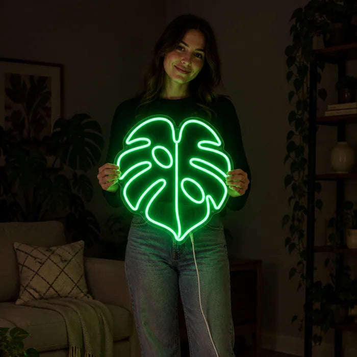 Monstera Leaf Neon LED Sign held by a woman, showing its size compared to her body