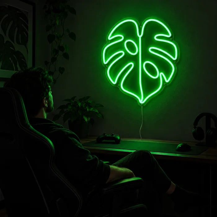 Monstera Leaf Neon LED Sign above a gaming desk, a gamer in a gaming chair in front of it