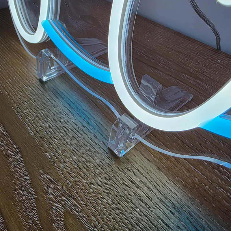 Detailaufnahme des beleuchteten Pokémon Neon-Zeichens auf zwei transparenten Acryl-Ständern auf einem Holzuntergrund