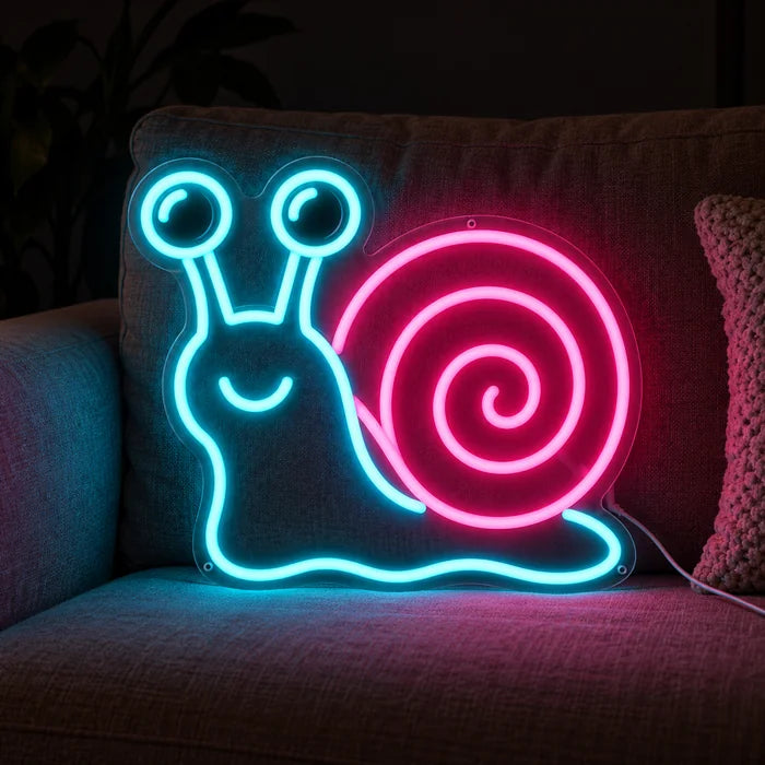Neon Snail Neon LED Sign on a cosy sofa between cushions and a throw