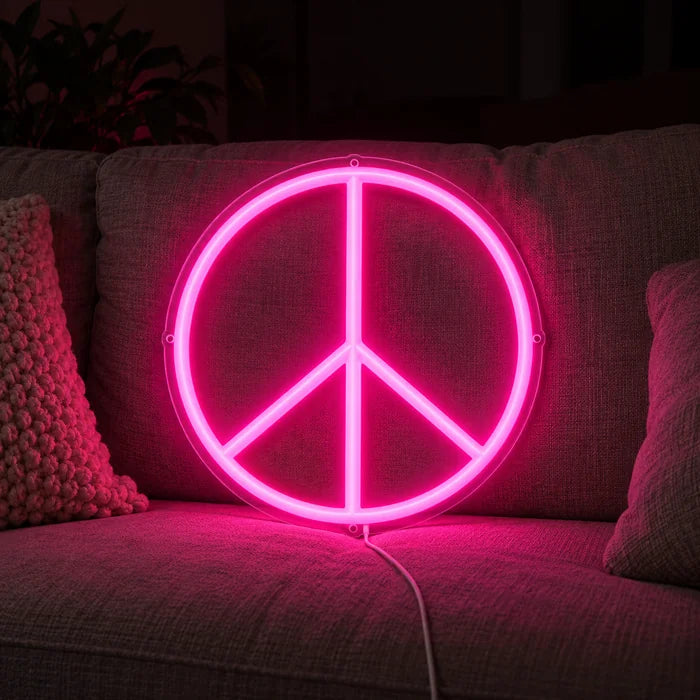 Peace neon LED skilt på en hyggelig sofa mellem puder og tæppe