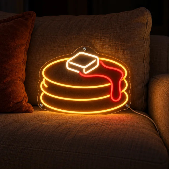 Pancakes Neon LED Sign on a cosy sofa between cushions and a throw