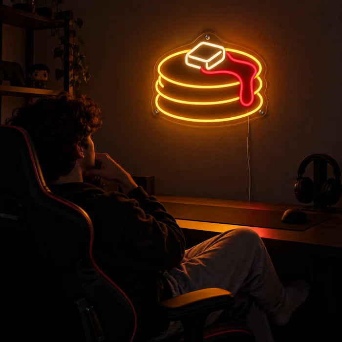 Pancakes Neon LED Sign above a gaming desk, a gamer in a gaming chair in front of it