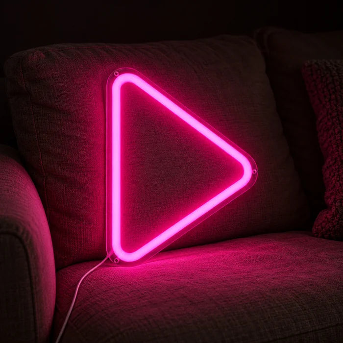 Play Button Neon LED Sign on a cosy sofa between cushions and a throw