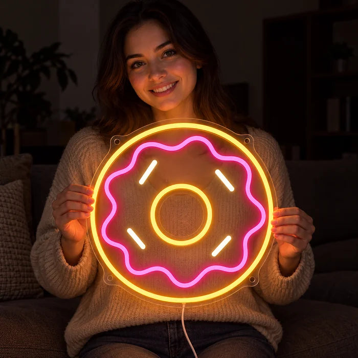 שלט ניאון LED דונאט ורוד בידיה של אישה מחייכת מול רקע כהה