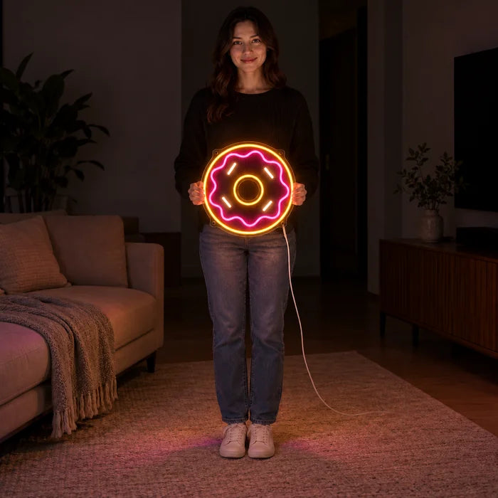 שלט ניאון LED דונאט ורוד מוחזק בידי אישה, מציג את הגודל ביחס לגוף