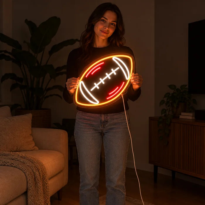 Rugbybold neon LED skilt holdt af en kvinde, viser størrelsen i forhold til kroppen