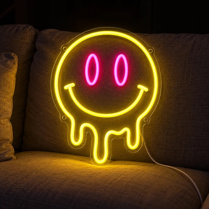 Melting Smiley Neon LED Sign on a cosy sofa between cushions and a throw