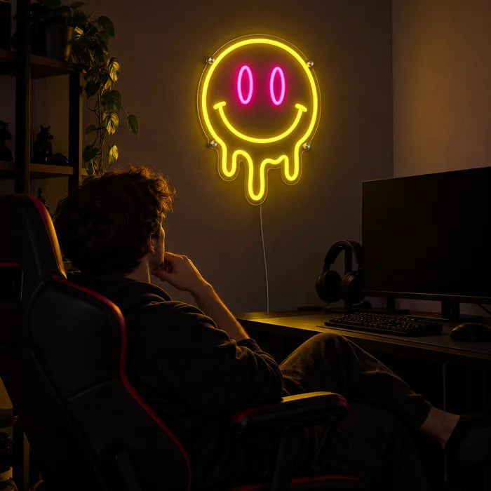 Melting Smiley Neon LED Sign above a gaming desk, a gamer in a gaming chair in front of it