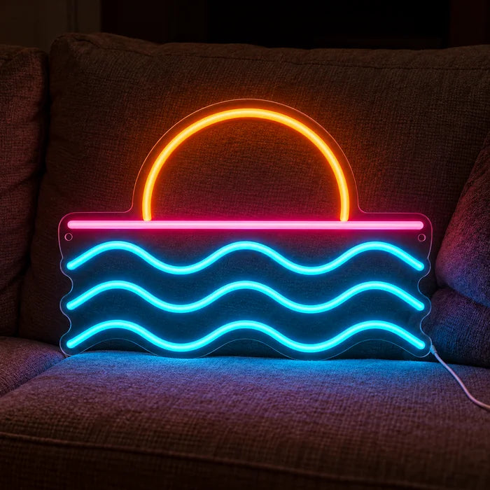Auringonlasku meren yllä neon LED -kyltti kodikkaalla sohvalla tyynyjen ja huovan välissä