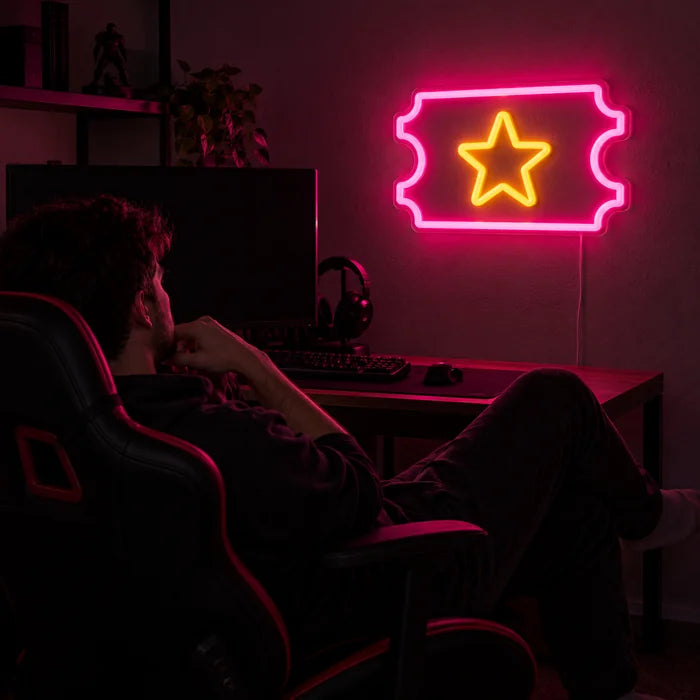 Star Ticket Neon LED Sign above a gaming desk, a gamer in a gaming chair in front of it