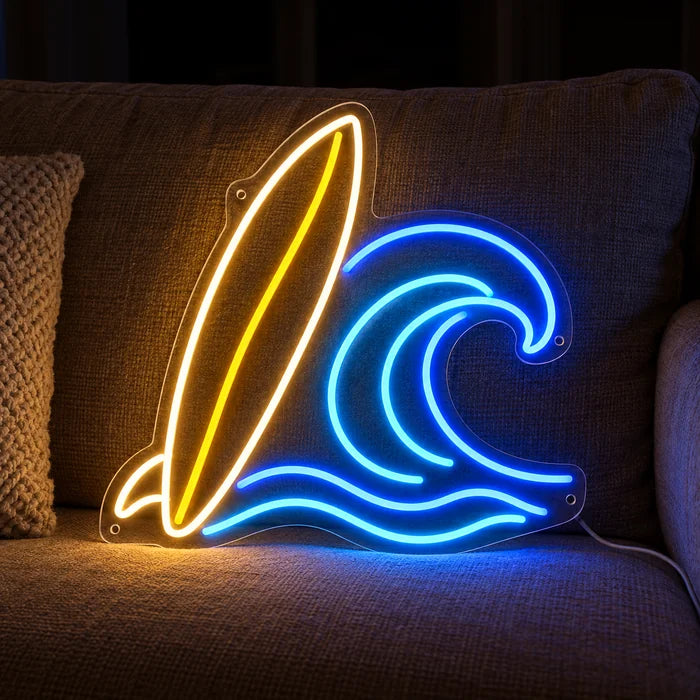 서프보드와 파도 네온 LED 사인, 아늑한 소파 위 쿠션과 담요 사이에 놓임